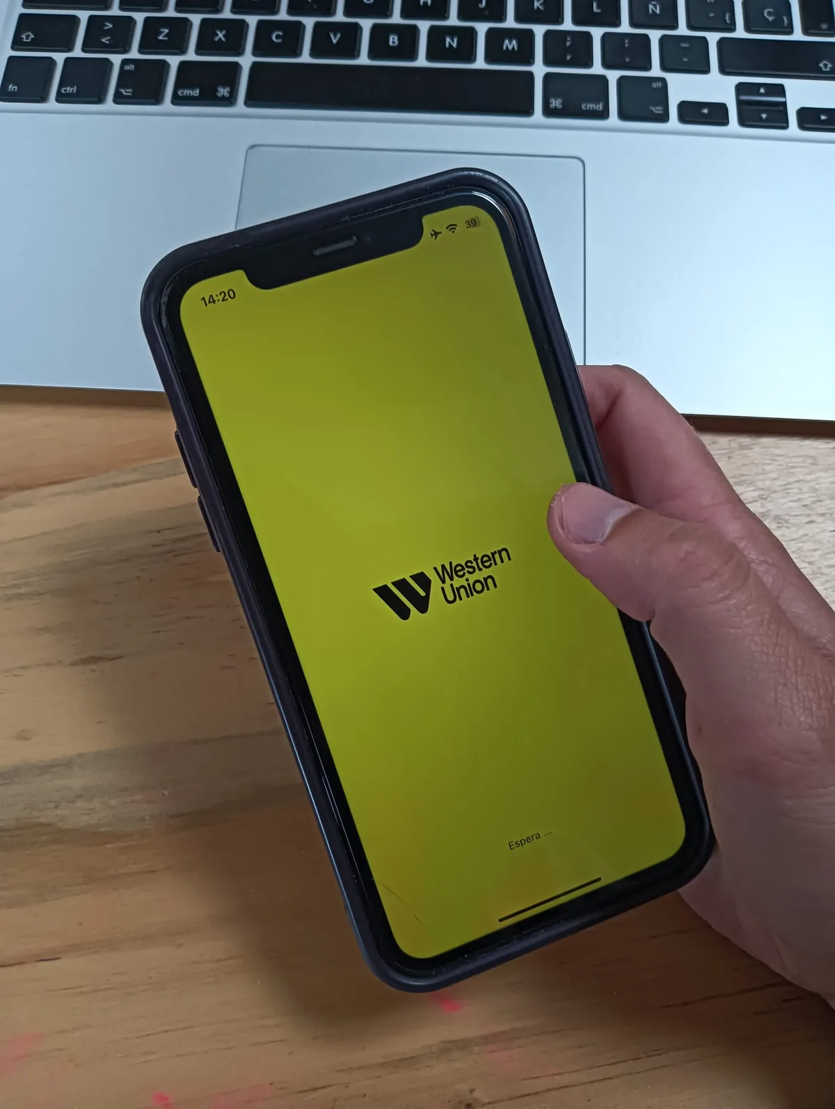 Mano usando la app de Western Union en el móvil para enviar o recibir dinero en ruta, esencial para viajeros overland