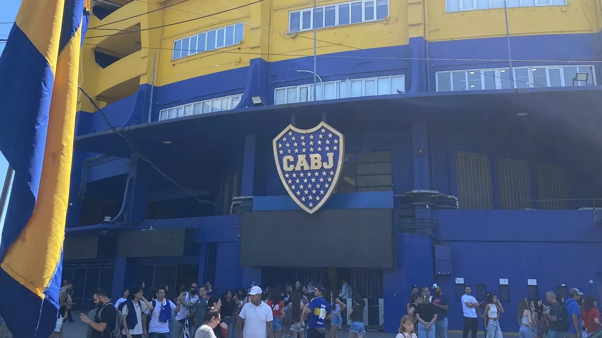 Fachada principal azul y amarilla de La Bombonera, estadio de Boca Juniors en Buenos Aires, con su escudo CABJ y gente