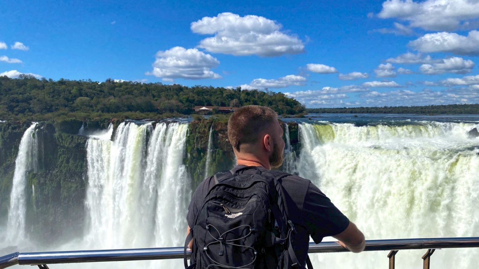 Viajero overland con mochila The North Face admirando las majestuosas Cataratas del Iguazú en un día soleado