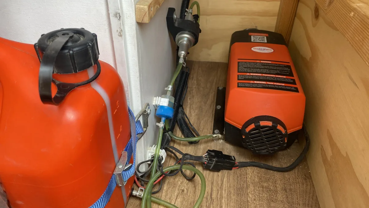 Calefactor diésel Qualified instalado en vehículo overland, junto a bidón de combustible naranja y mangueras de alimentación