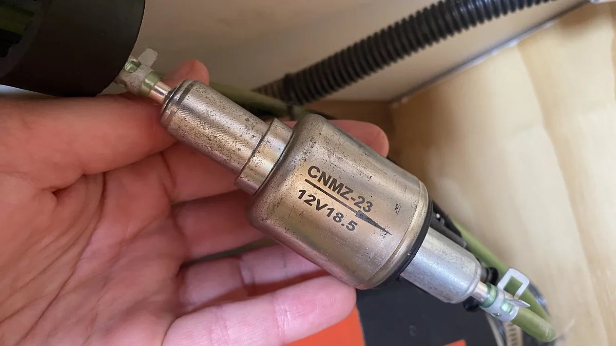 Mano sosteniendo una bomba de combustible diésel 12V CNMZ-23 para calefacción estacionaria en furgoneta camper