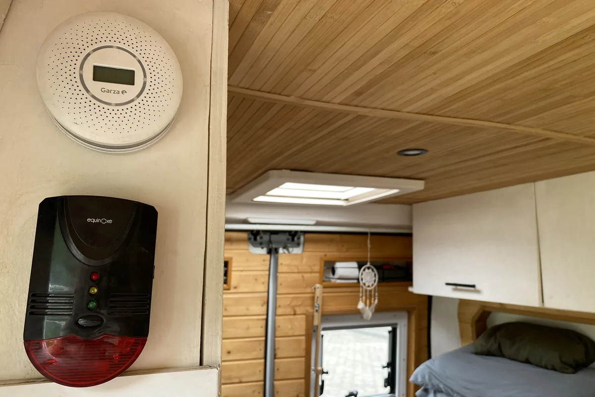 Detalles interior furgoneta camper: detector de gas Garza, alarma Equinux, techo de bambú, claraboya y zona cama