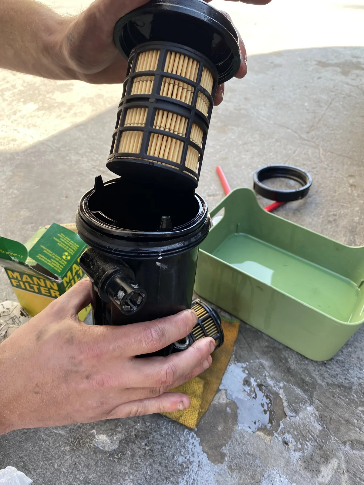 Manos sustituyendo el filtro de combustible MANN FILTER de un vehículo overland durante una parada técnica