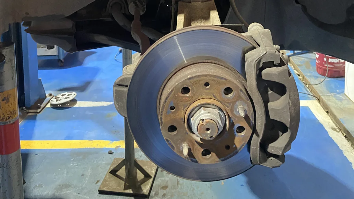 Frenos delanteros expuestos de una van de viaje en el taller, preparando el mantenimiento esencial para nuevas rutas