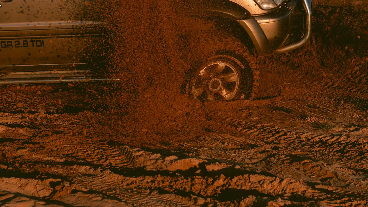 Vehículo 4x4 Nissan Patrol GR 2.8 TDI con bull bar, lanzando barro al circular por una pista overland