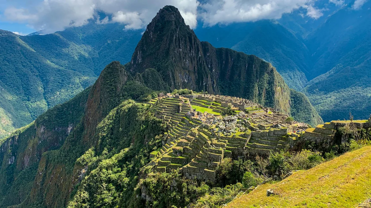 Impresionante vista panorámica de Machu Picchu y Huayna Picchu, la antigua ciudad inca entre montañas verdes en Perú