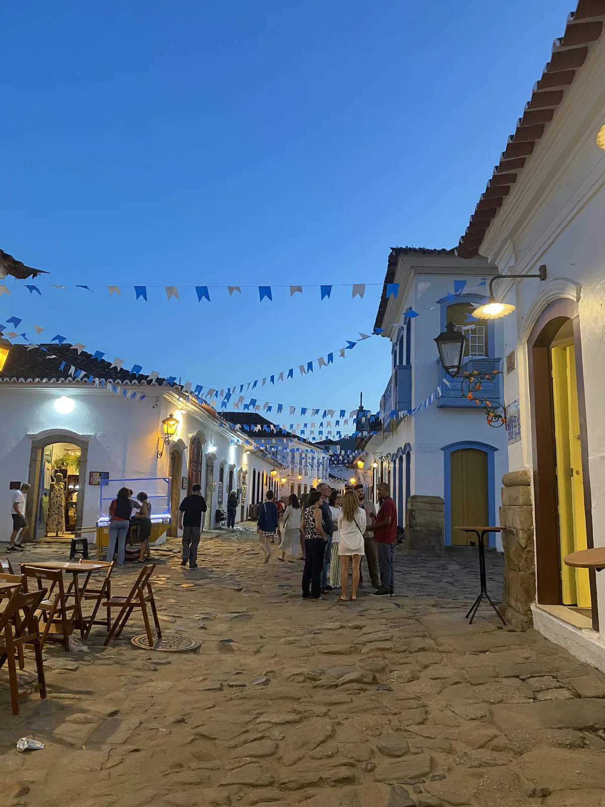 Calle adoquinada de Paraty al anochecer. Edificios coloniales blancos y azules con gente disfrutando la noche