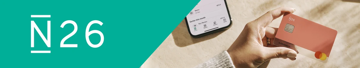 N26, cuenta sin comisiones en el extranjero: mano con una tarjeta rosa junto a un móvil con la app