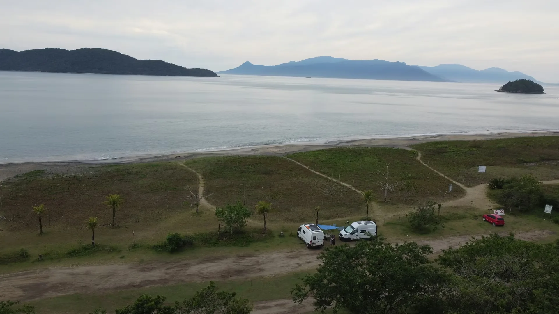 Dos furgonetas estacionadas delante de una playa de Brasil, con el mar de fondo