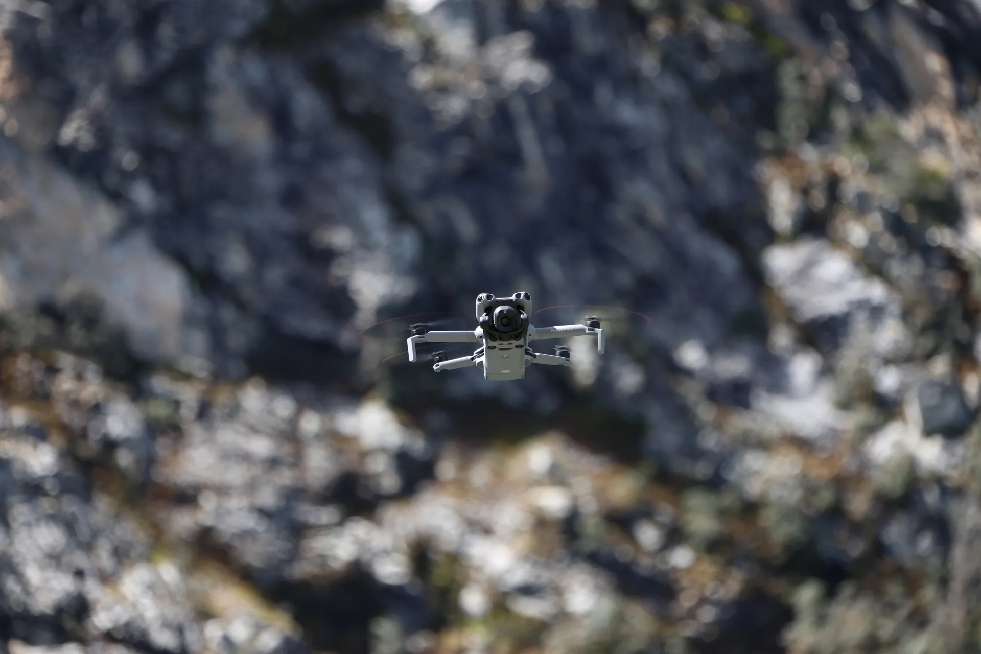 Drone DJI mini 5 volando, con un fondo de roca detrás