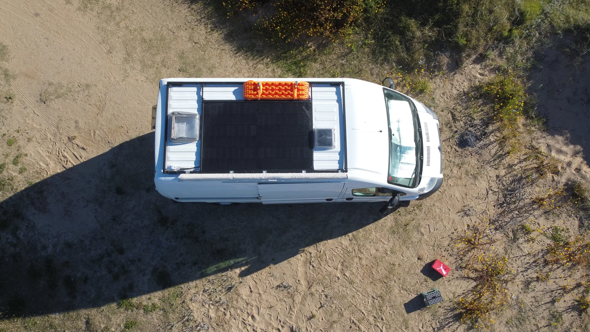 Furgoneta camper blanca vista desde el cielo con una baca y una placa solar en el techo