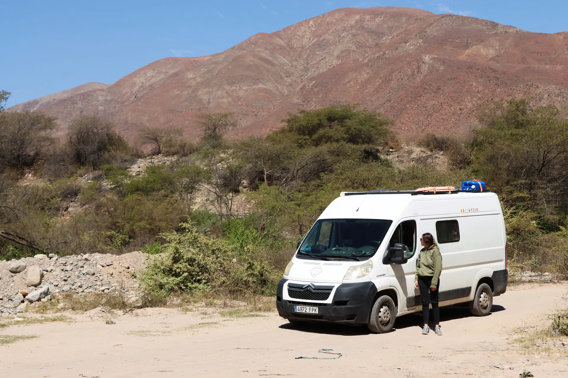 Mujer de pie junto a una furgoneta camper blanca