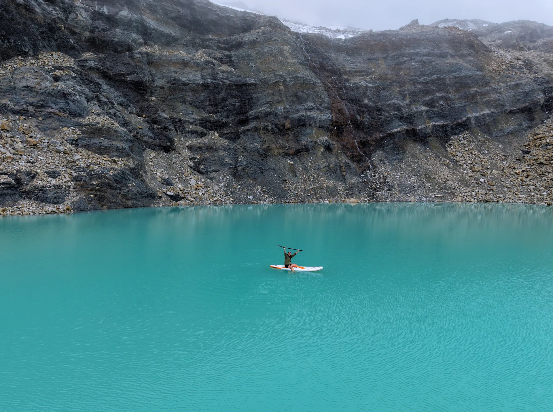 Mujer haciendo paddle surf en una laguna helada en la cordillera de los Andes