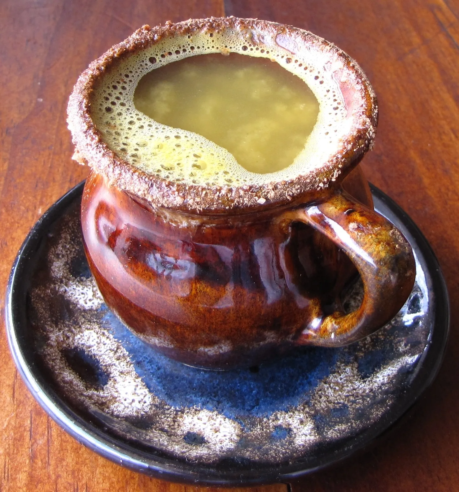 Taza de canelazo caliente servida en una jarrita de barro tradicional andina