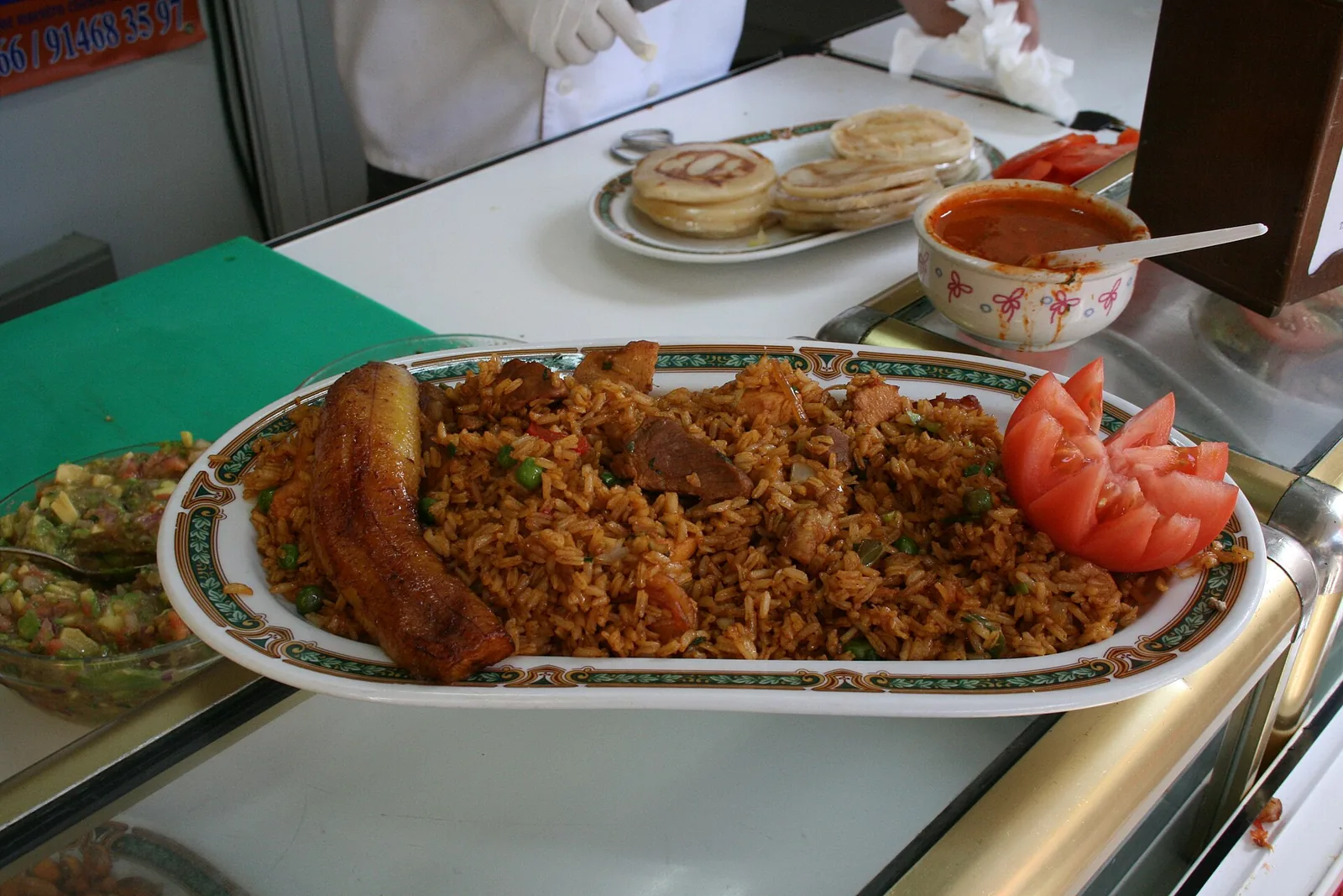 Ración de lechona con arroz, cerdo y arveja, servida con plátano maduro y tomate
