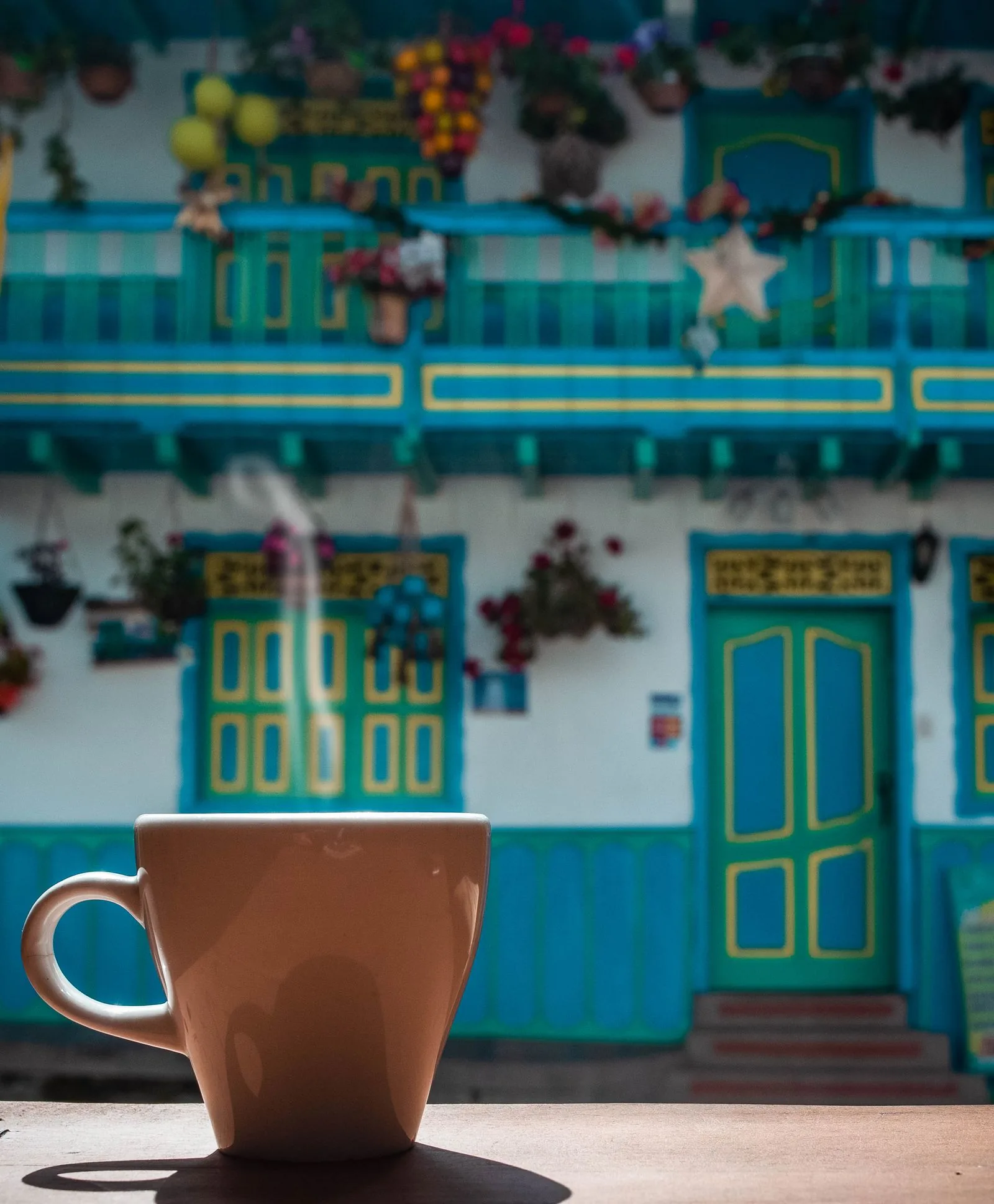 Taza de café humeante frente a una fachada colonial de balcones de colores en Salento