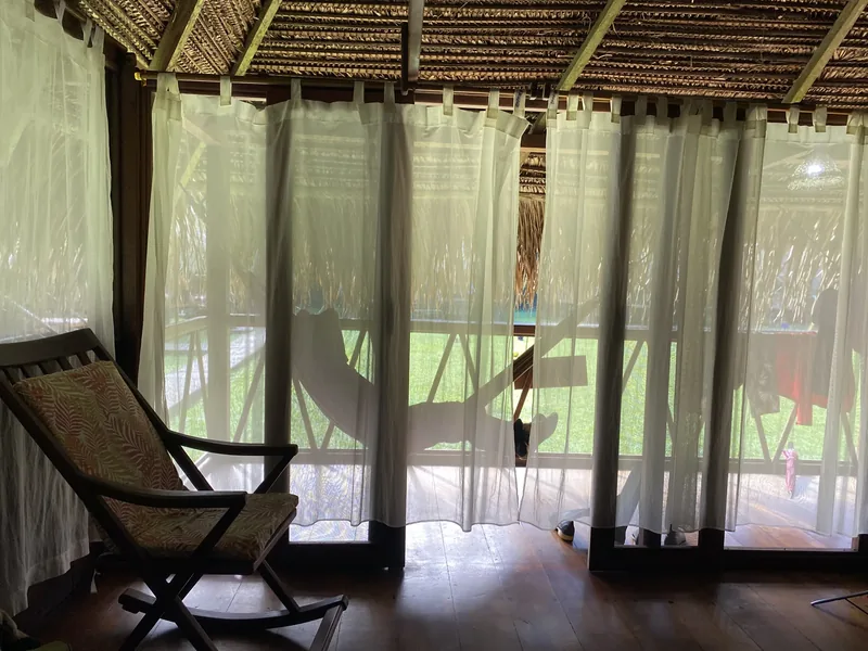 Cabaña del lodge con techo de paja y hamaca en el balcón