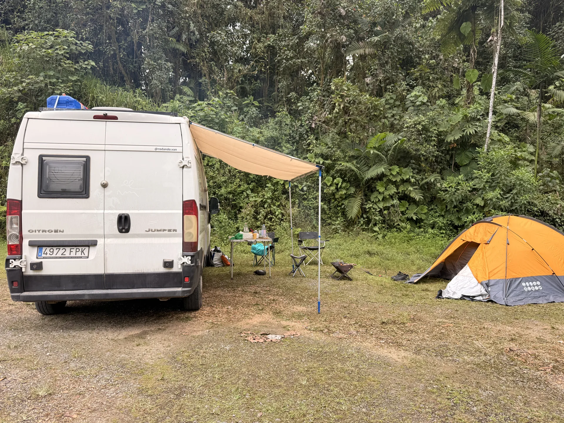 Furgoneta camper blanca junto a una tienda de campaña