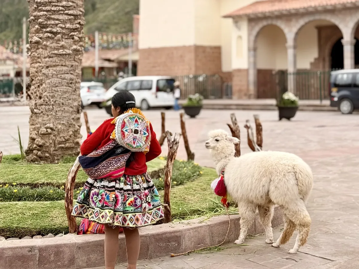 Mujer con una llama en una plaza de un pueblo