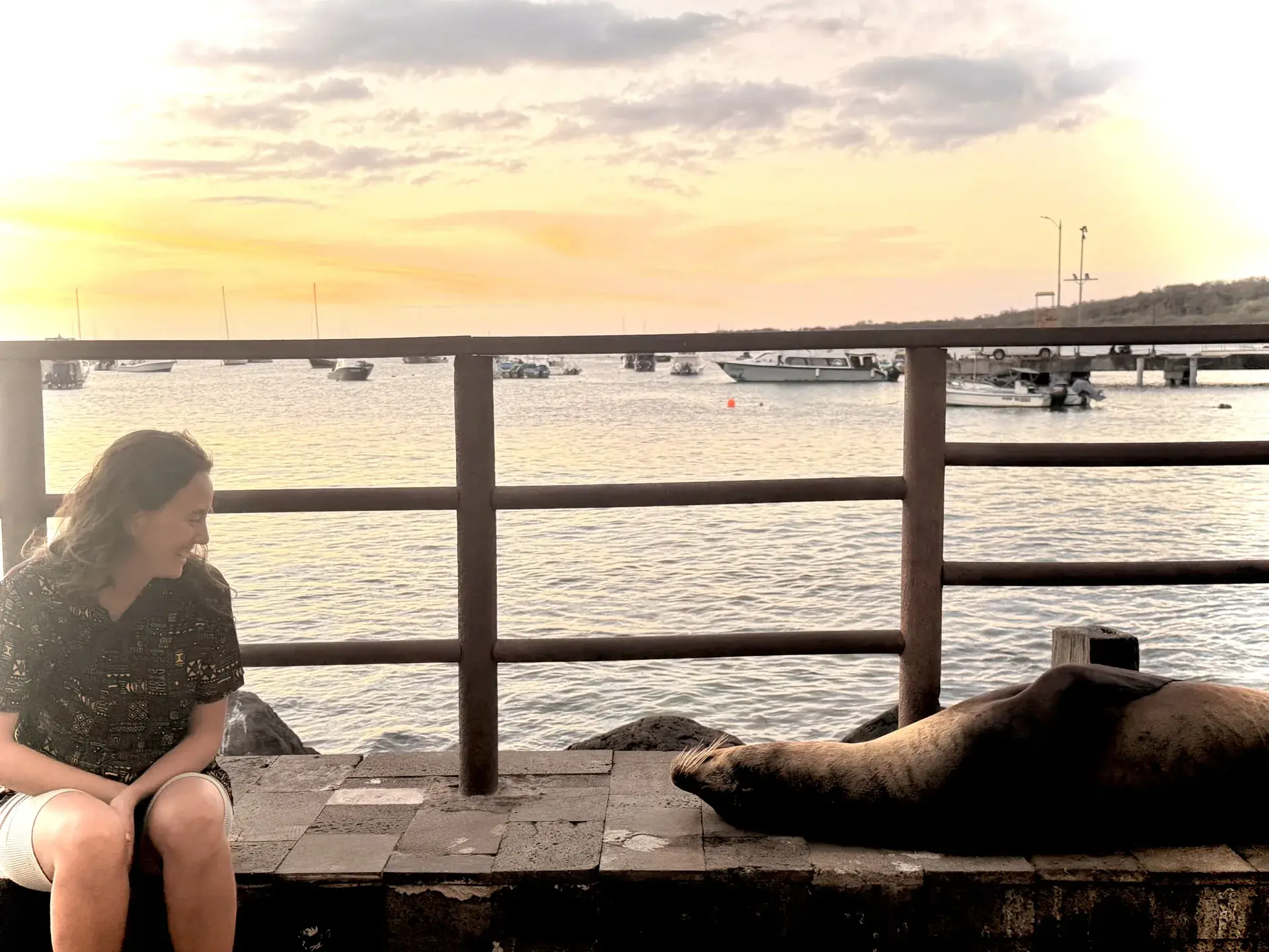 Mujer sentada al lado de un lobo marino, Galápagos