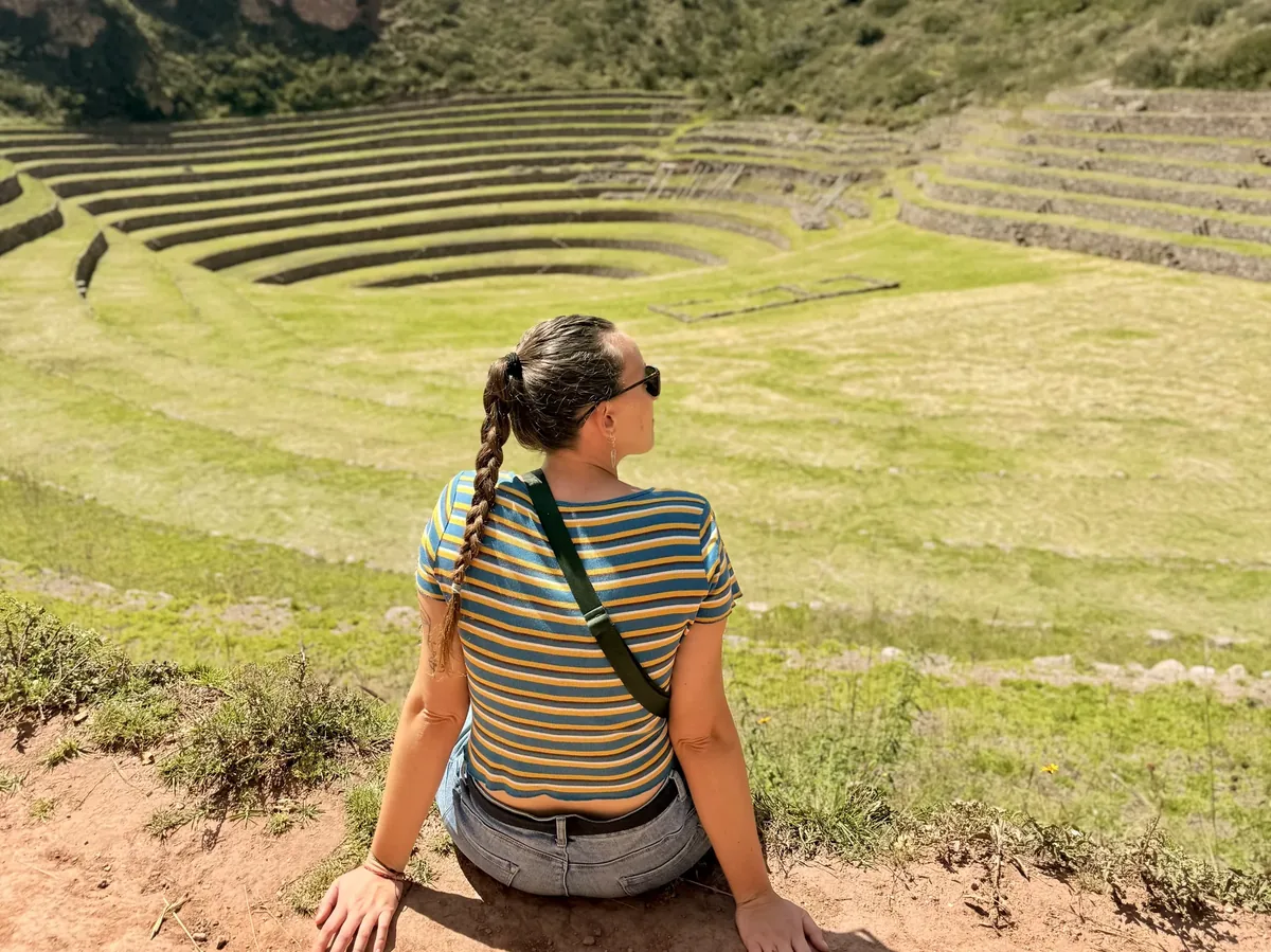 mujer sentada en los andenes de Moray, Perú