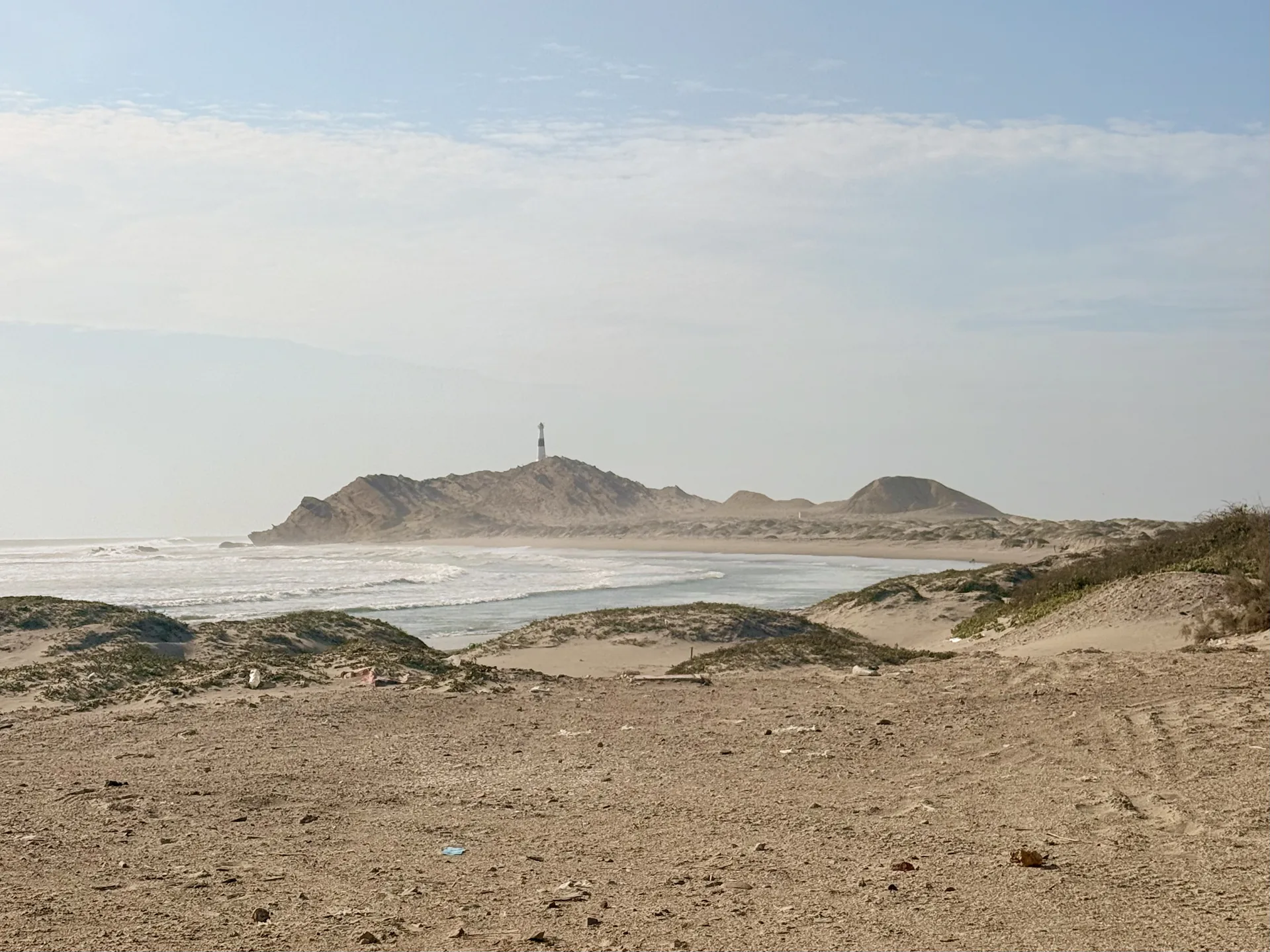 Playa con un faro a lo lejos