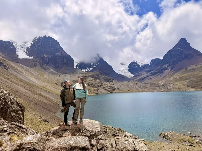 Pareja junto a una laguna glaciar rodeada de picos nevados en la cordillera Real, cerca de La Paz (Bolivia)